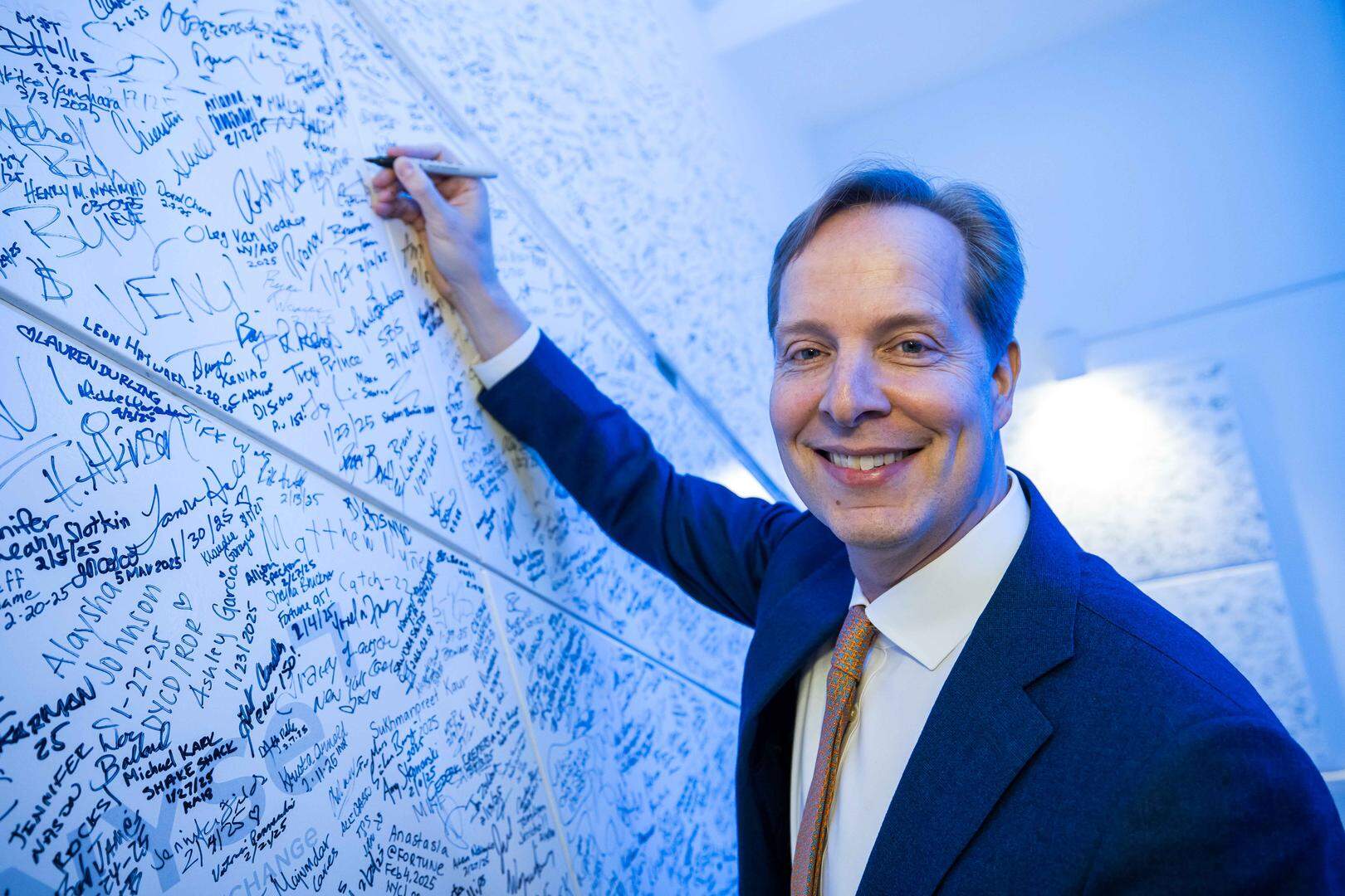 Almar Latour signeert de beroemde muur van de New York Stock Exchange, waar iedereen die de beurs opent en sluit zijn naam mag opschrijven.